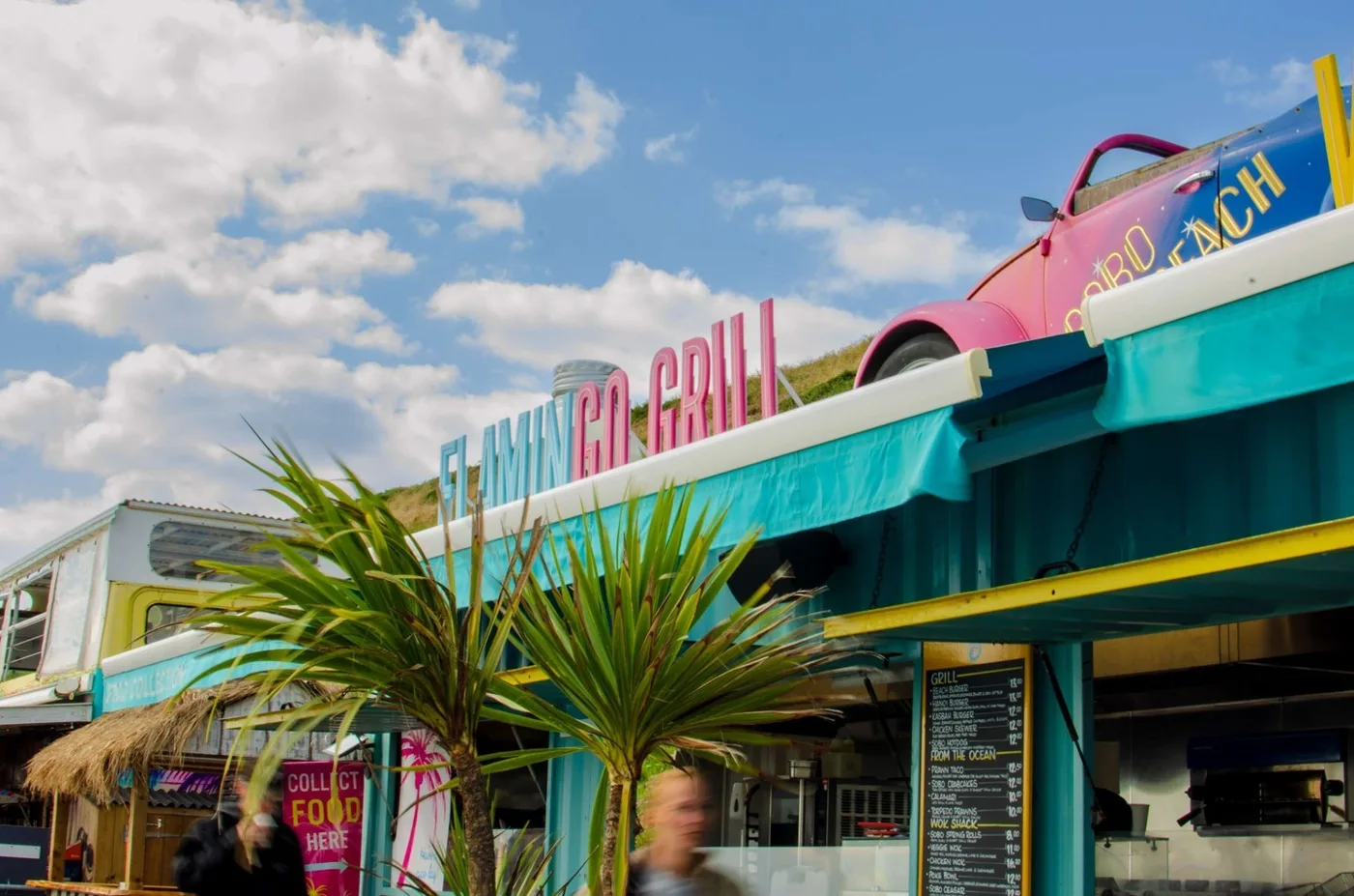 The Flamingo Grill counter at SOBO Beach, with palm plants in front and a pink car on the roof